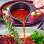 red wine jus being poured onto cooked meat