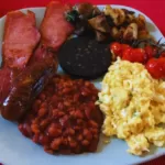 Full English breakfast: bacon, egg, sausage, tomatoes, mushrooms, black pudding, beans, and fried potatoes